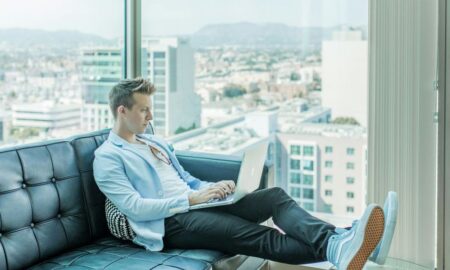 man sitting on sofa while using laptop