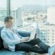 man sitting on sofa while using laptop