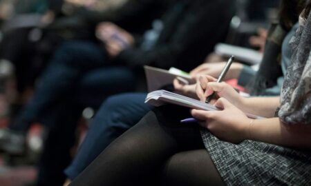 selective focus photography of people sitting on chairs while writing on notebooks