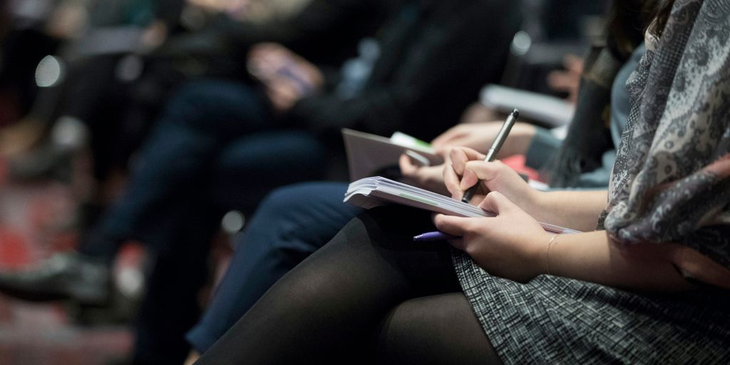 selective focus photography of people sitting on chairs while writing on notebooks